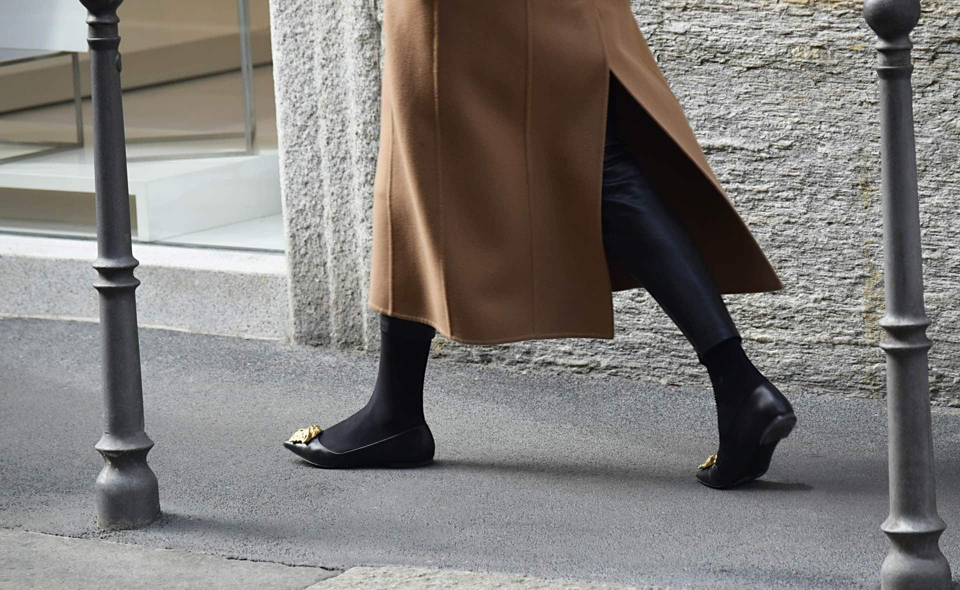 Nahaufnahme einer Frau mit schwarzen Schuhen beim Gehen auf dem Fußgängerweg