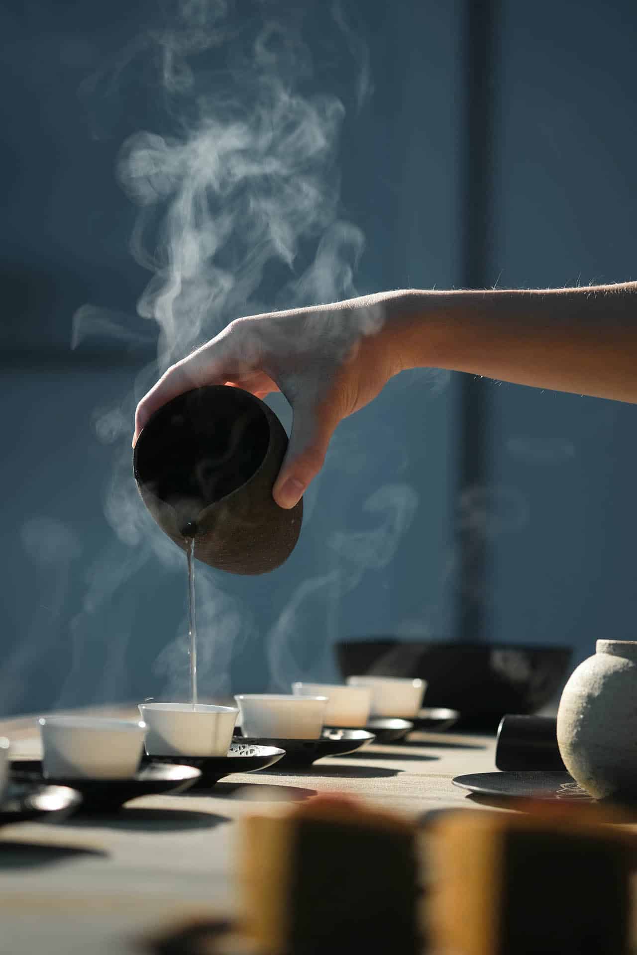 Eine Hand gießt Tee in kleine Tassen aus einem Keramikhalter im Wellnesshotel in Bad Krozingen